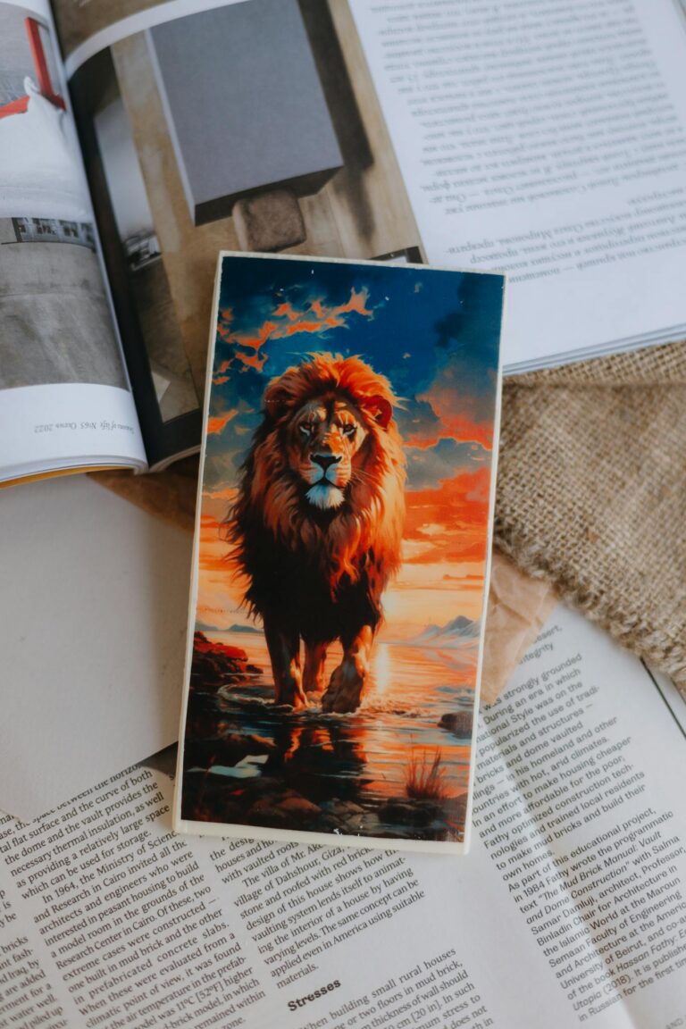 Creative lion artwork placed on open magazines, depicting a majestic lion against a sunset background.